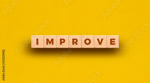 Improve - word written on wooden blocks with yellow background