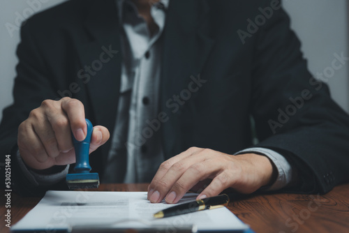 Man stamping approval of work finance banking or investment marketing documents on desk.