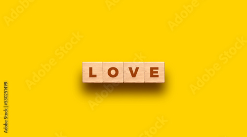 LOVE - word written on wooden blocks with yellow background