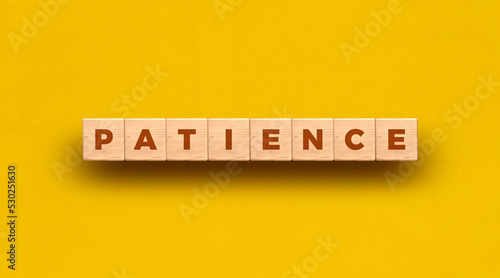 Patience - word written on wooden blocks with yellow background