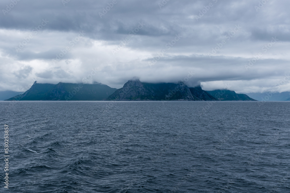 Cloud covered mountains on the shore of Northern Norway. Dramatic seascape in summer, Norwegian sea, Atlantic ocean.