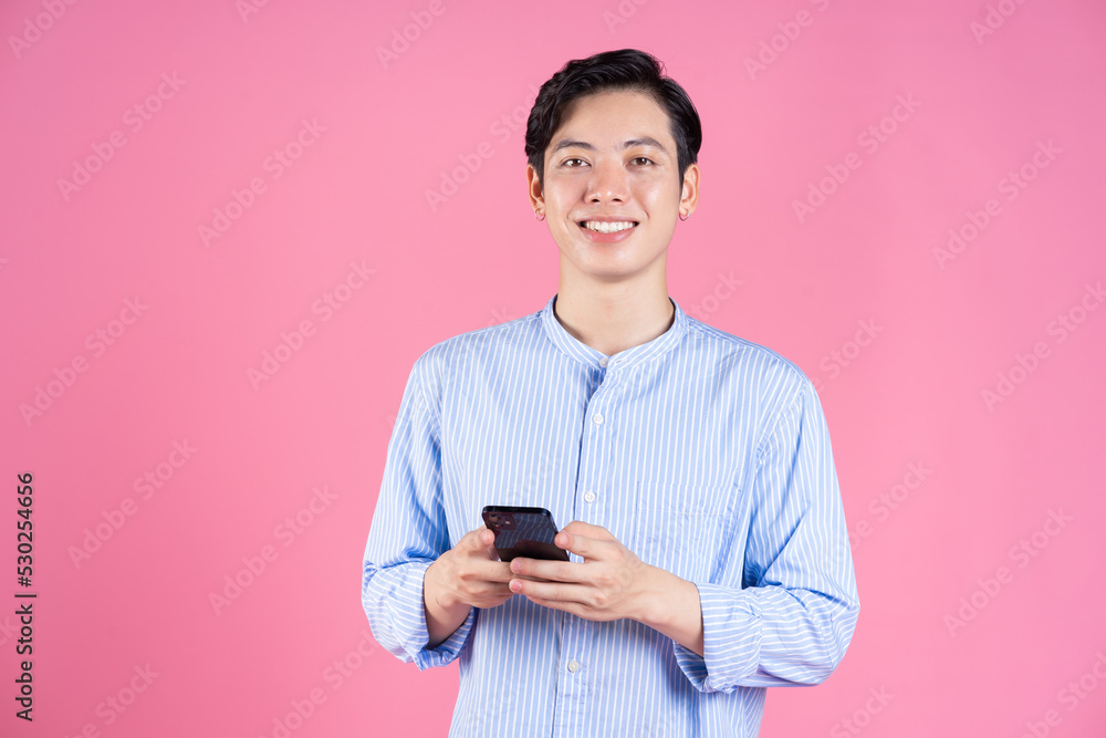 Photo of young Asian man using smartphone on background Photo of young Asian man using smartphone on background