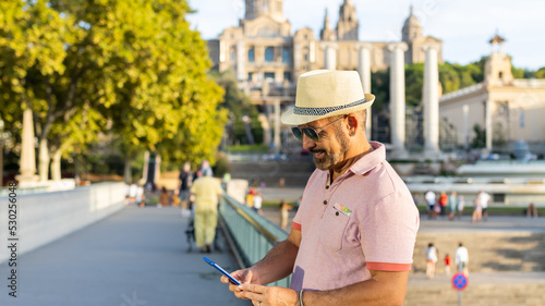 Man with a happy cap checking his cell phone in Montjuic in Barcelona (Spain).