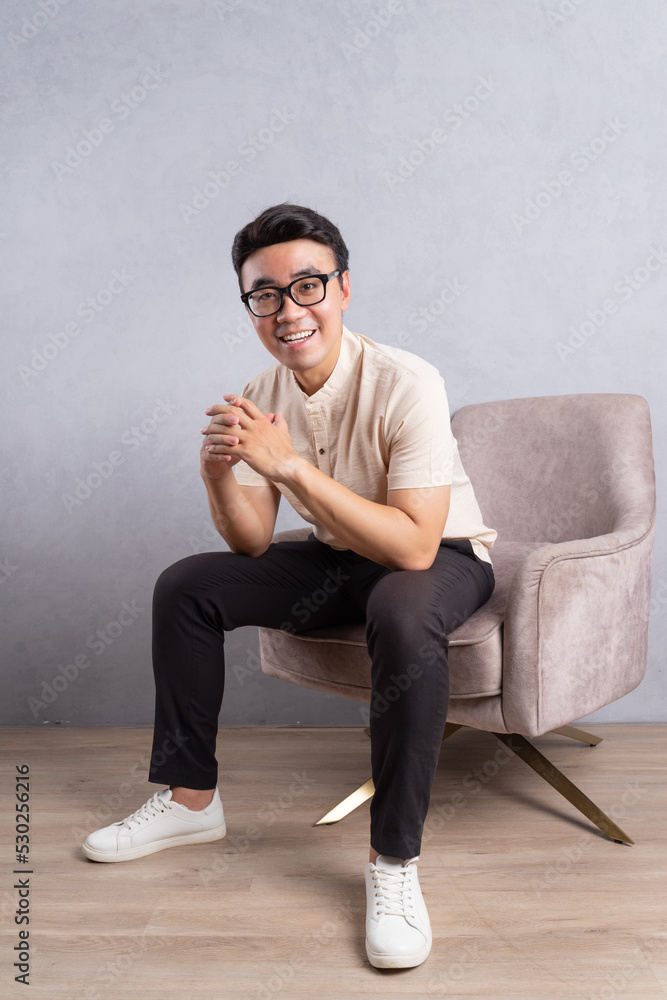 Image of young Asian man sitting on chair Image of young Asian man sitting on chair