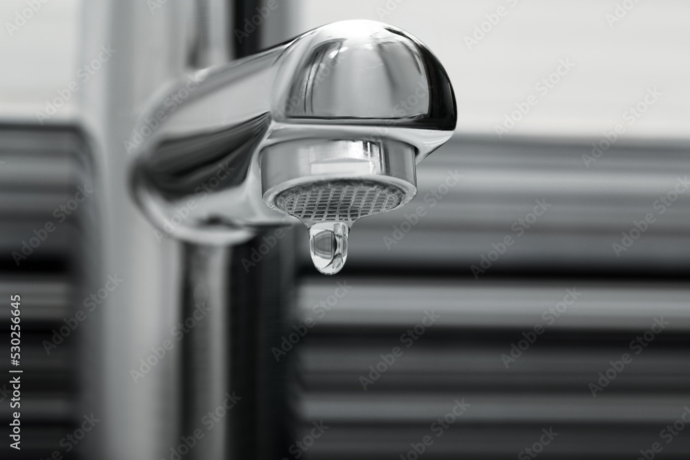 Water drop falling down from tap in bathroom, closeup Water drop falling down from tap in bathroom, closeup
