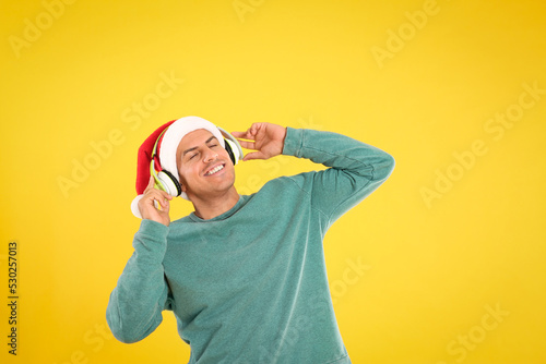 Happy man with headphones on yellow background. Christmas music © New Africa