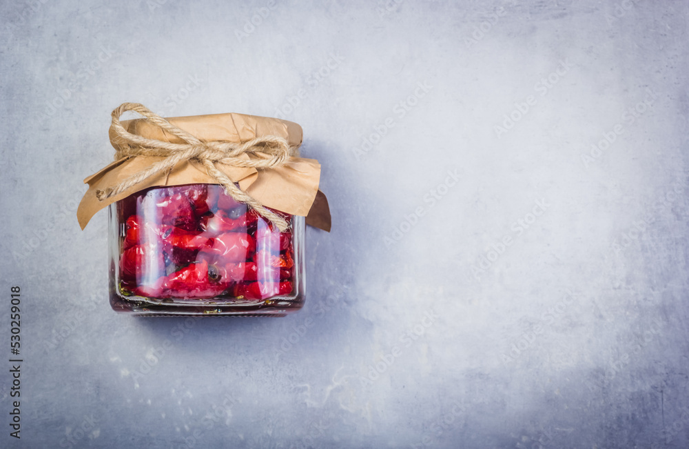 Homemade sundried tomatoes on a gray background. Dried tomatoes in a jar copy space