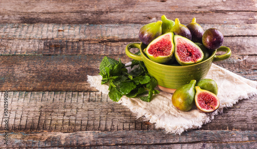 Fresh ripe green figs in a bowl on a wooden background.
