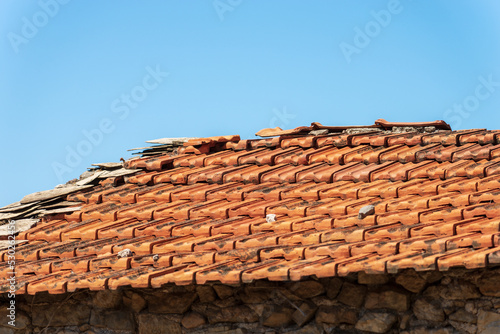 Close-up of an old house roof with a terracotta tiles (clay), on a clear blue sky with copy space. Liguria, Italy, Europe.