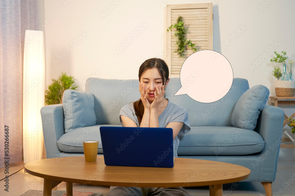 夜のリビングでノートパソコンを見て困っている女性 吹き出しあり 夜のリビングでノートパソコンを見て困っている女性 吹き出しあり