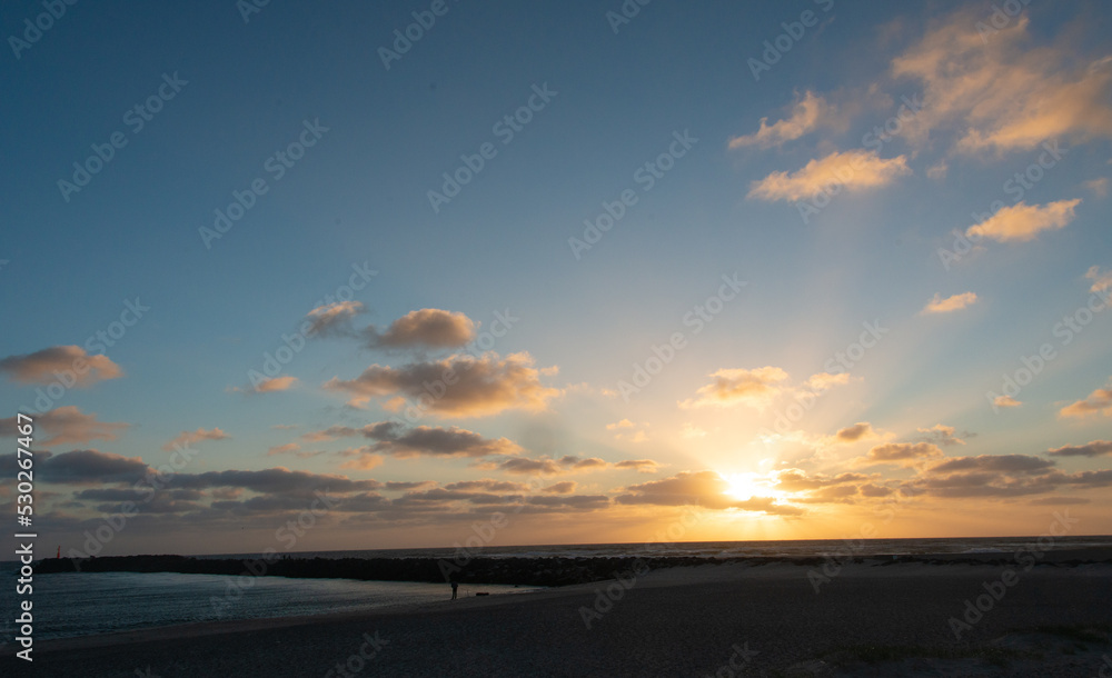 Strand Landschaft mit Mole vor bewölkten Himmel während des Sonnenuntergangs