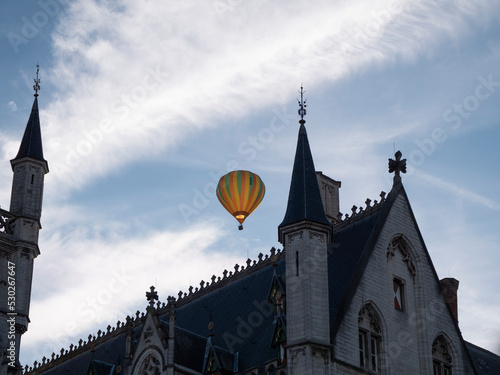 Colorful hot air balloon flies over the neo-gothic town hall of the city of Sint Niklaas in Belgium