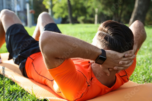 Man wearing fitness tracker during training in park photo