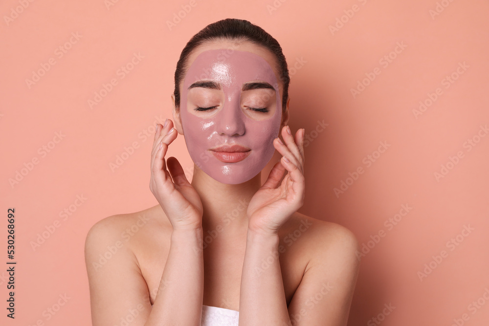 Woman with pomegranate face mask on pale coral background Woman with pomegranate face mask on pale coral background