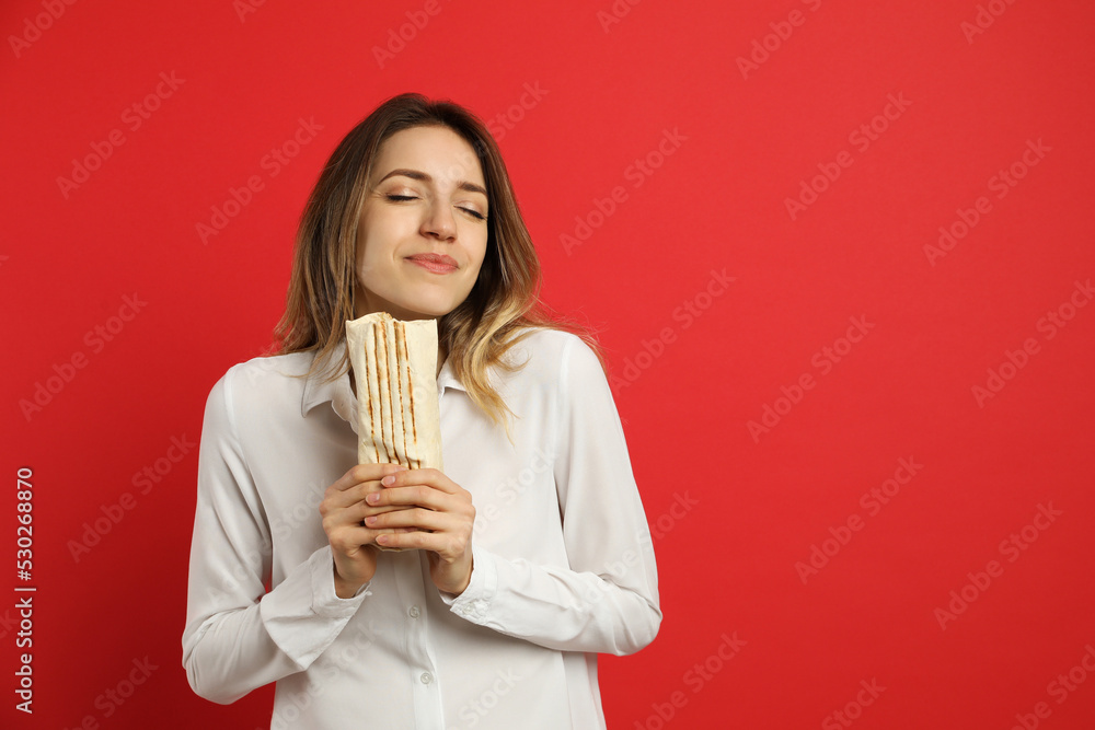 Young woman with delicious shawarma on red background, space for text Young woman with delicious shawarma on red background, space for text