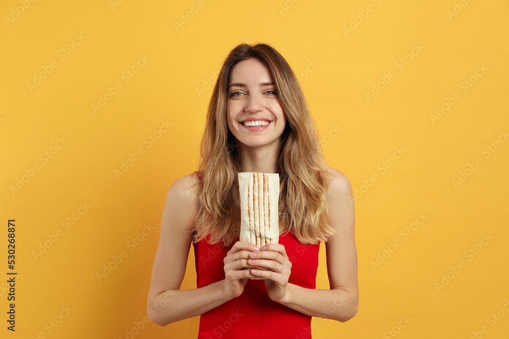 Young woman with delicious shawarma on yellow background Young woman with delicious shawarma on yellow background