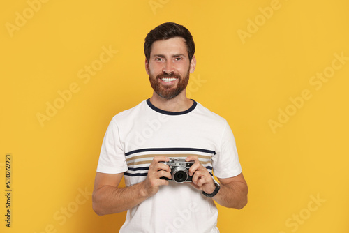 Man with camera on yellow background. Interesting hobby © New Africa