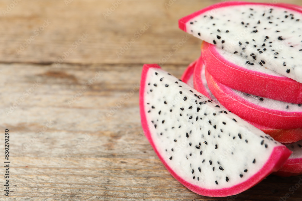 Slices of delicious dragon fruit (pitahaya) on wooden table, closeup. Space for text