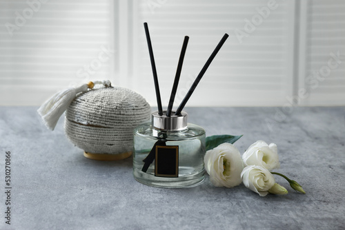 Reed diffuser, box and eustoma flowers on gray marble table