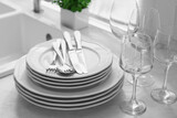 Different clean dishware, cutlery and glasses on countertop in kitchen, closeup