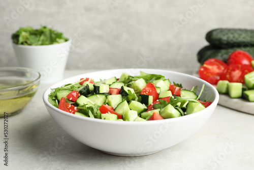 Delicious salad with cucumbers  tomatoes and sesame seeds in bowl on light table