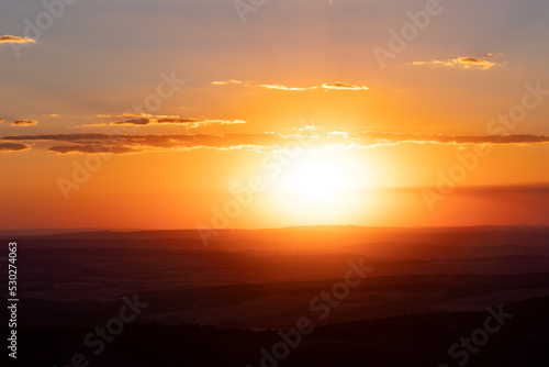 View from Feldberg mountain in Hessen, Germany. Wide landscape with hills and clouds during sun goes down.