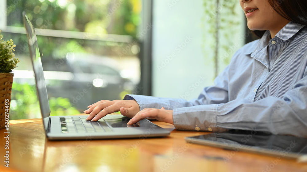 Side view young woman employee hands typing business email on her laptop computer Side view young woman employee hands typing business email on her laptop computer