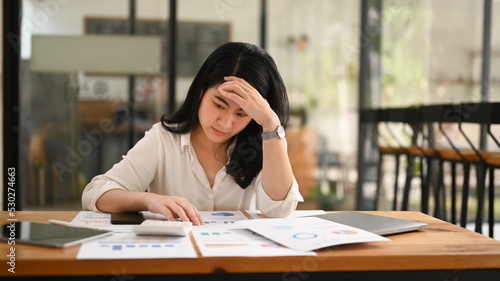 Stressed business woman suffering from migraine headache, considering financial problem solution