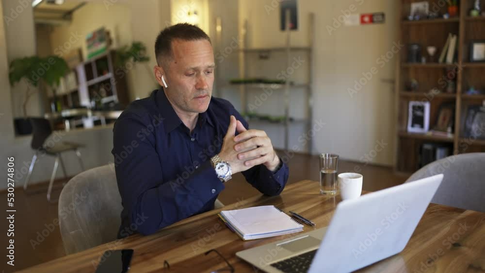 Adult businessman in headphones discussing important things using video call Adult businessman in headphones discussing important things using video call