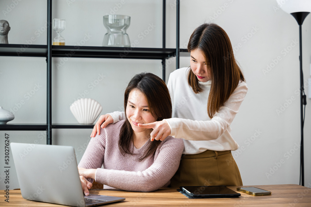 Asian mother and teenage daughter looking at laptop computer at home office, happy family work together, middle age woman and teen they shoping online on computer Asian mother and teenage daughter looking at laptop computer at home office, happy family work together, middle age woman and teen they shoping online on computer