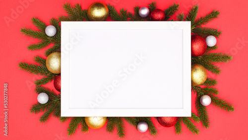 White copy space frame surrounded with gold and red Chrsitmas balls and fir branches. FLat lay WInter holidays concept