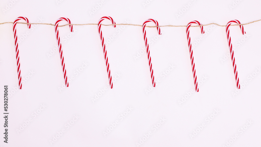 Christmas candy canes hanged on rope on white background with copy space. Flat lay Christmas candy canes hanged on rope on white background with copy space. Flat lay