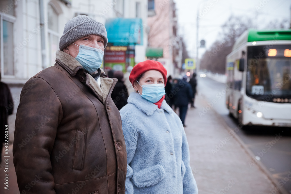 Woman and elderly man in protective medical masks on street. Woman and elderly man in protective medical masks on street.