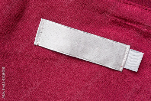 Blank white laundry care clothes label on red fabric texture background