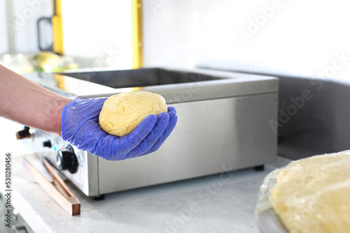 Making Hungarian langos in a protective gloves, in a food truck, restaurant. Hungarian fast-food, a deep fried flatbread photo