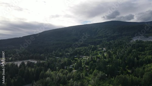 Lush coastal mountains underneath a cloudy sky at British Columbia's sunshine coast in summer. Aerial fly over view photo