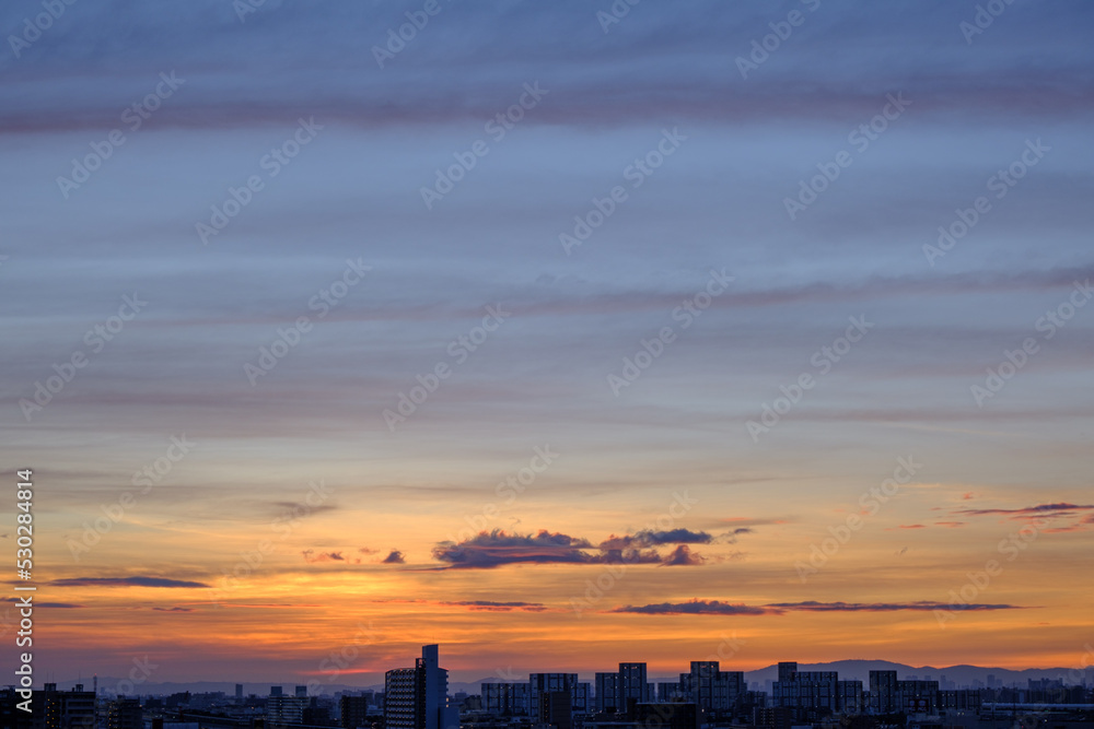 都市の夜明け。東の空が明るくなり雲がまだ昇る前の太陽に照らせら美しいグラデーションを見せる。神戸市内から大阪方面を臨む。