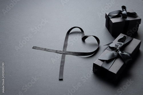 Composition of presents with ribbons and ribbon heart on gray background