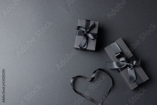 Composition of presents with ribbons and ribbon heart on gray background