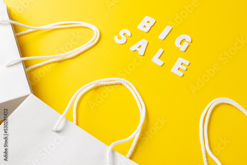 Composition of paper bags and big sale text on yellow background