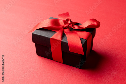 Composition of present with red ribbon on red background