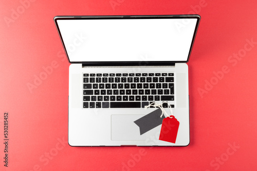 Composition of laptop and gift tags on pink background