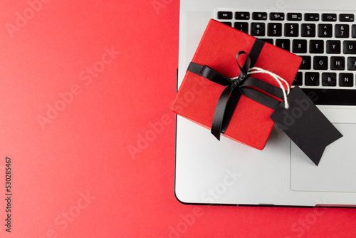 Composition of laptop with gift tag and present on pink background