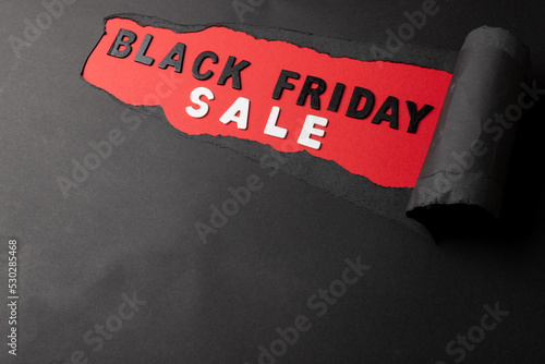 Composition of black paper and black friday sale text on red background