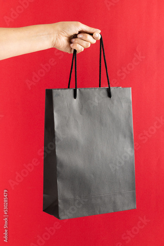 Composition of hand holding shopping bag on pink background