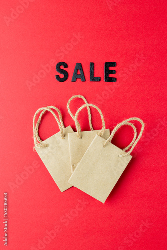 Composition of sale text and paper shopping bags on pink background