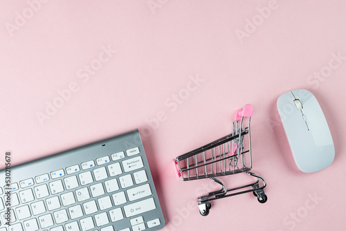 Composition of keyboard, mouse and shopping cart on white background