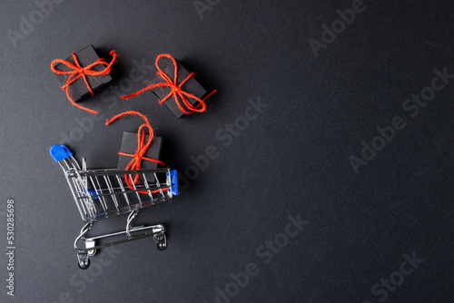 Composition of shopping cart with presents and copy space on gray background
