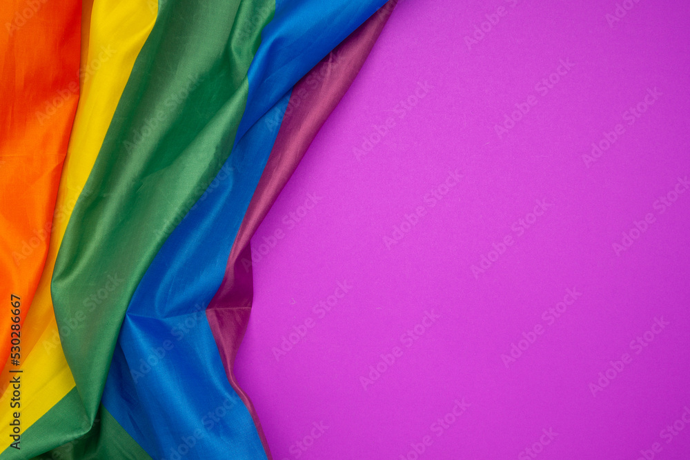 The rainbow flag or LGBT is on a purple background with copy space for text