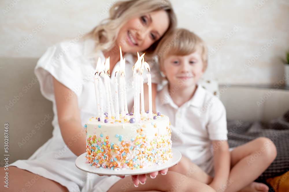 Happy woman and boy celebrating the child birthday at home. The kid blows out the candles in the birthday cake Happy woman and boy celebrating the child birthday at home. The kid blows out the candles in the birthday cake